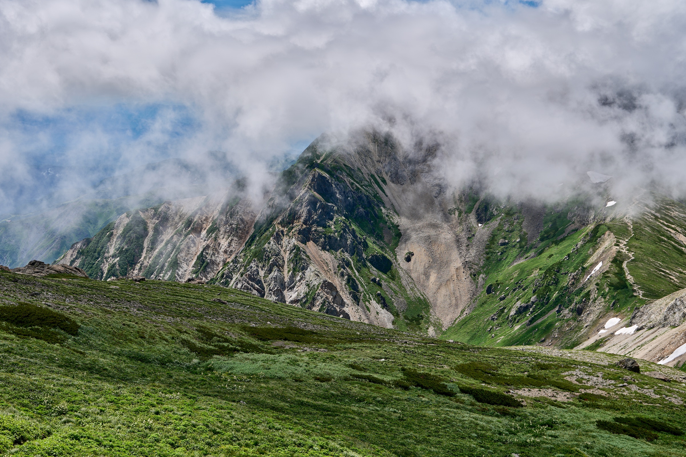 A mountain face partially concealed by dense low cloud