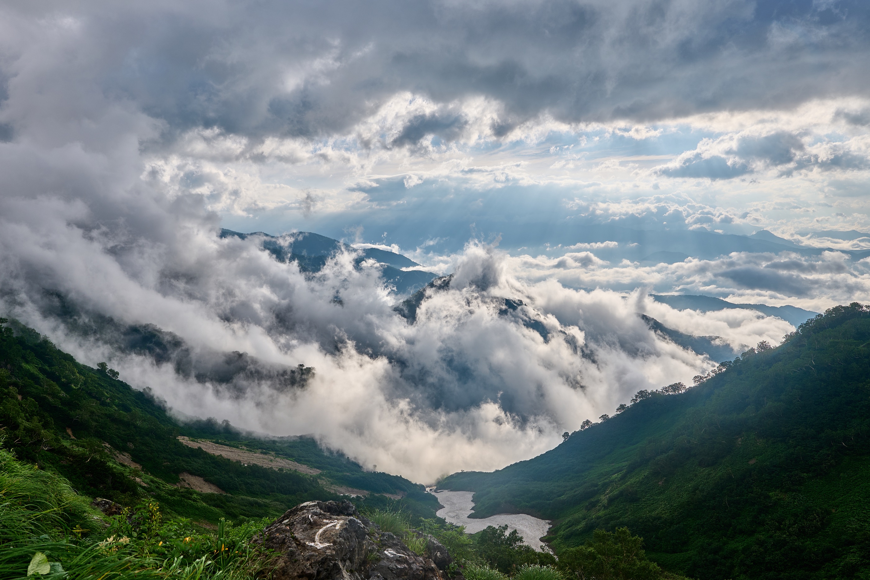 Cloud lifting to reveal a layered alpine valley and ridges