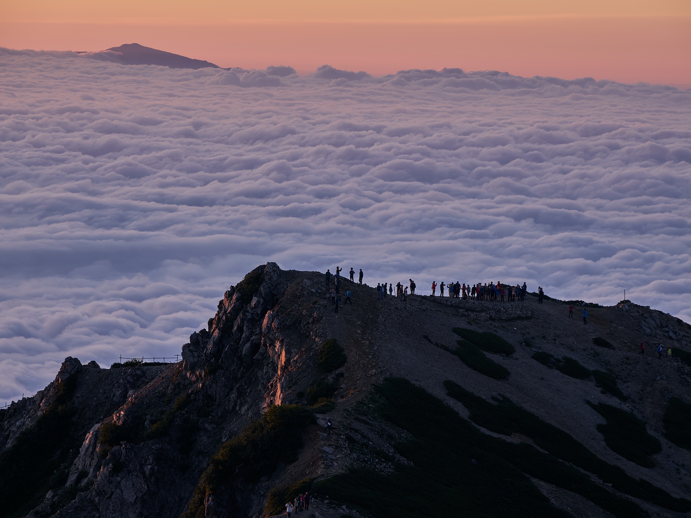 A mountain ridge emerging in clear dawn light above distant cloud