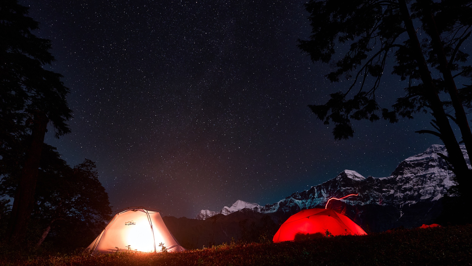 Two illuminated tents beneath the stars and Gurja Himal